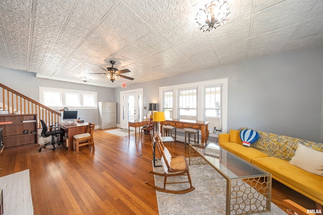 living room with ceiling fan with notable chandelier and hardwood / wood-style floors