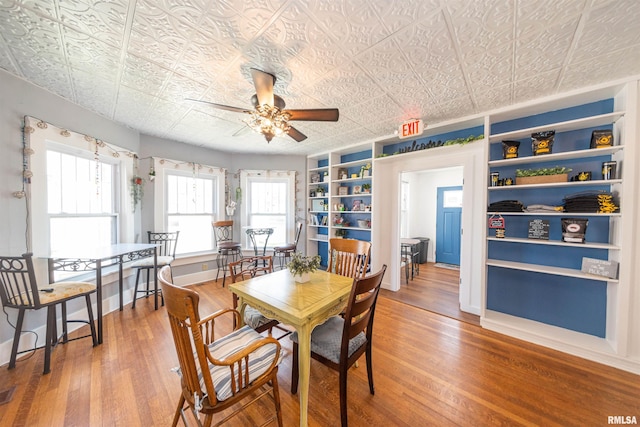 dining space with ceiling fan, built in shelves, a healthy amount of sunlight, and hardwood / wood-style floors