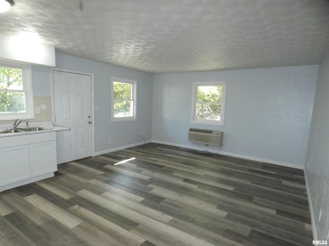 interior space featuring sink, a textured ceiling, dark hardwood / wood-style flooring, and a wall unit AC