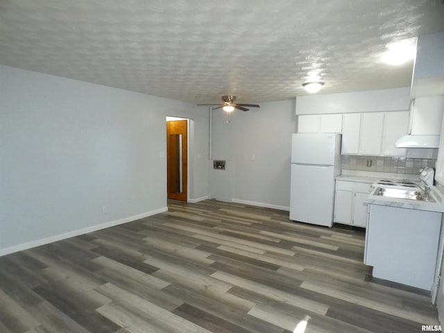 kitchen featuring a textured ceiling, white refrigerator, backsplash, and white cabinets