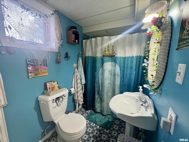 bathroom with toilet, a shower with curtain, a drop ceiling, and sink