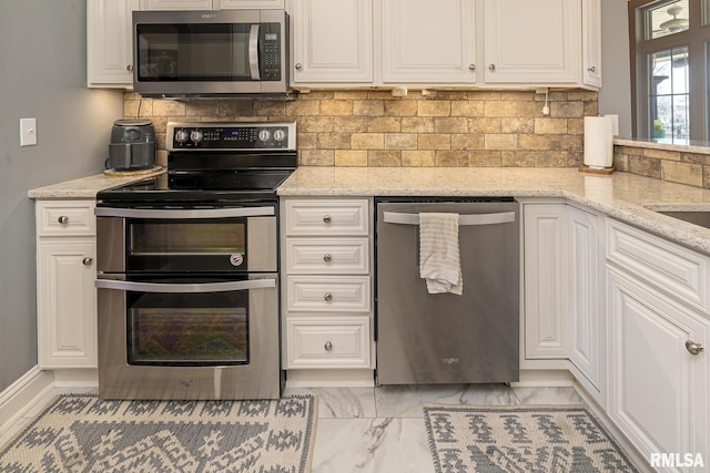 kitchen featuring light stone counters, backsplash, white cabinetry, and stainless steel appliances