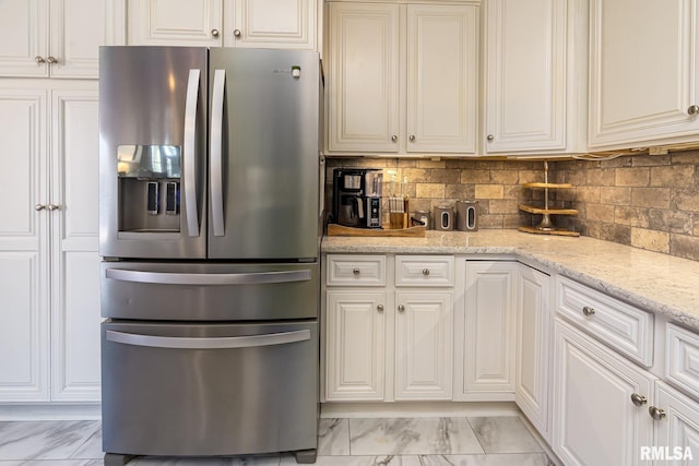 kitchen featuring tasteful backsplash, stainless steel refrigerator with ice dispenser, light stone countertops, and white cabinetry