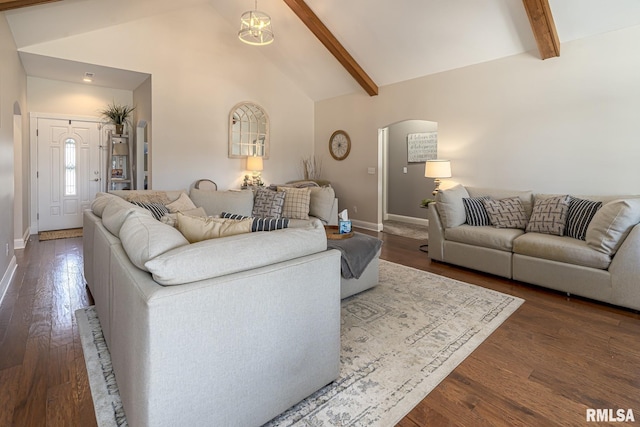 living room featuring arched walkways, dark wood-style flooring, baseboards, and beam ceiling