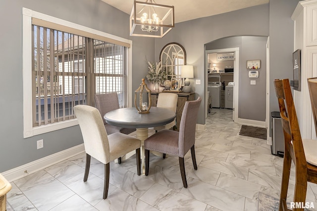 dining room with arched walkways, washing machine and clothes dryer, marble finish floor, and an inviting chandelier