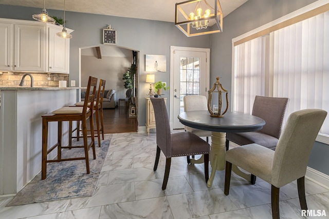 dining space featuring a chandelier, marble finish floor, and baseboards