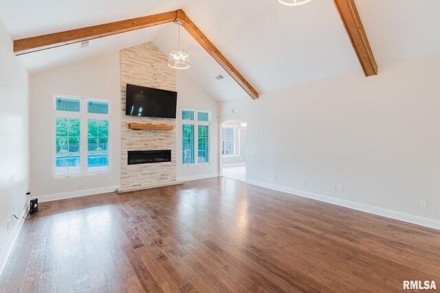 2730 Kokopelli Dr, Marion, IL 62959 - unfurnished living room featuring wood finished floors, beam ceiling, high vaulted ceiling, plenty of natural light, and a stone fireplace