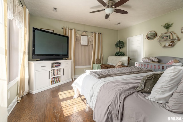 bedroom with dark wood-style flooring, visible vents, baseboards, and a ceiling fan
