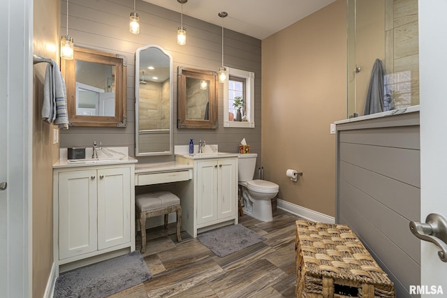 full bath featuring toilet, two vanities, a sink, and baseboards