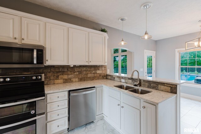 2730 Kokopelli Dr, Marion, IL 62959 - kitchen with appliances with stainless steel finishes, a sink, a peninsula, tasteful backsplash, and light stone countertops