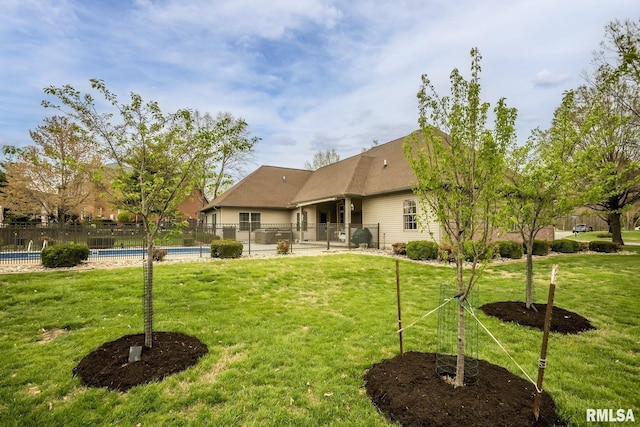 back of house with a fenced in pool, fence, and a lawn
