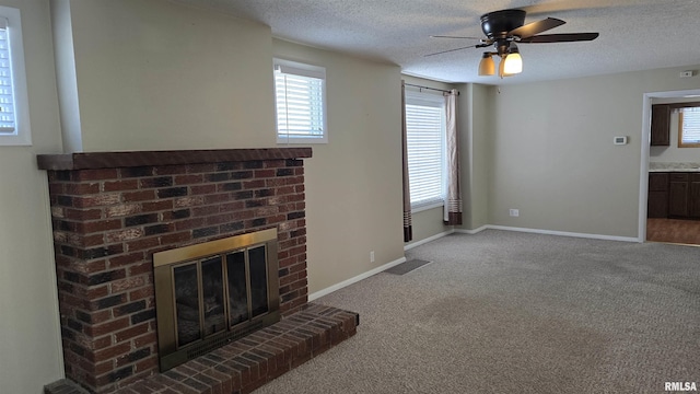 unfurnished living room featuring a textured ceiling, a brick fireplace, carpet flooring, and ceiling fan