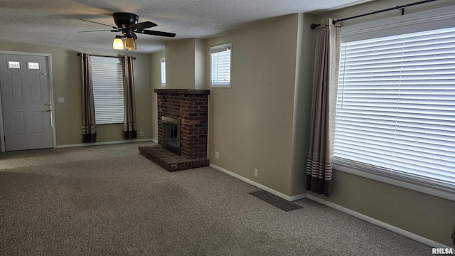 unfurnished living room featuring ceiling fan, a textured ceiling, carpet flooring, and a fireplace