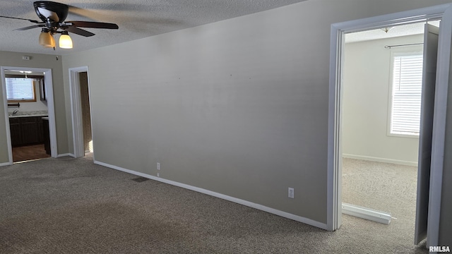 carpeted spare room featuring ceiling fan and a textured ceiling