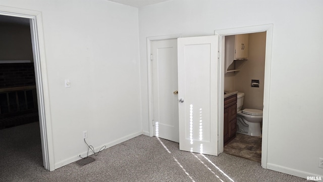 unfurnished bedroom with a spacious closet, carpet floors, and ensuite bath