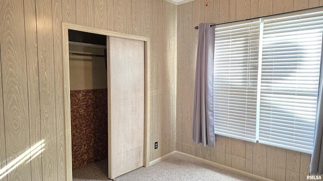 unfurnished bedroom with a closet, carpet flooring, and wood walls