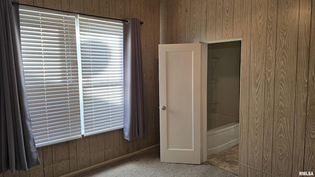 bathroom featuring a tub and wooden walls