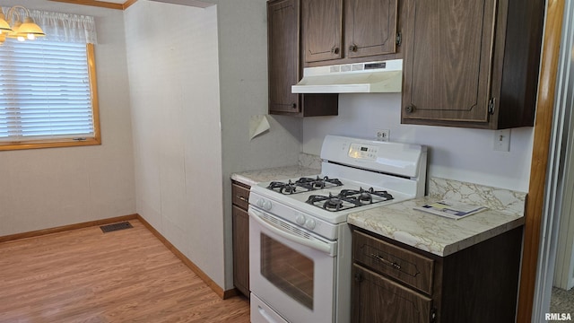 kitchen featuring dark brown cabinetry, light hardwood / wood-style floors, and white range with gas cooktop