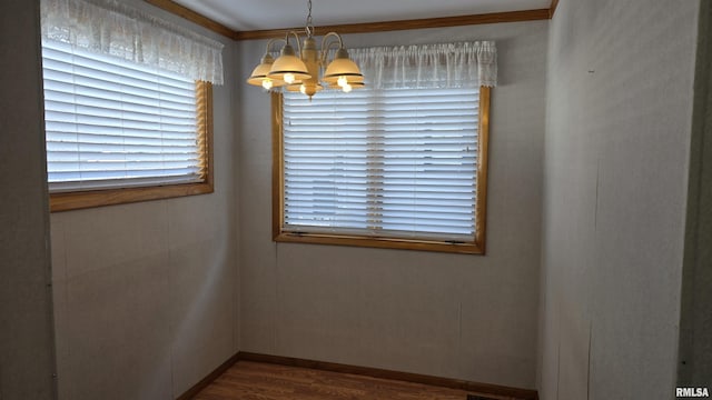 empty room with hardwood / wood-style flooring, crown molding, and a chandelier