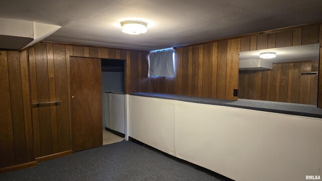 interior space featuring dark carpet and wood walls