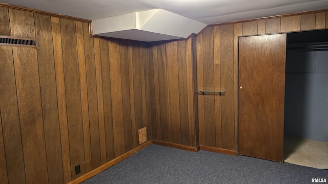 interior space with dark carpet and wooden walls