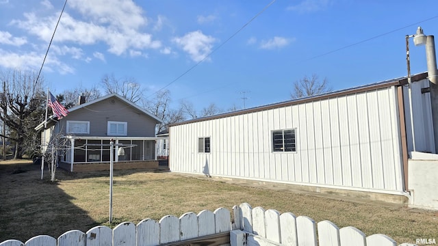 rear view of property featuring a sunroom and a lawn