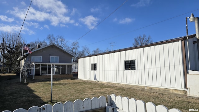 rear view of property featuring a sunroom and a lawn