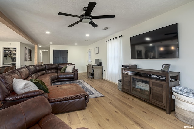 living room featuring light hardwood / wood-style floors, a textured ceiling, and ceiling fan