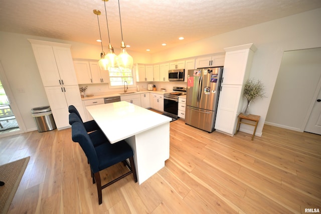 kitchen with sink, white cabinetry, a breakfast bar, a kitchen island, and stainless steel appliances