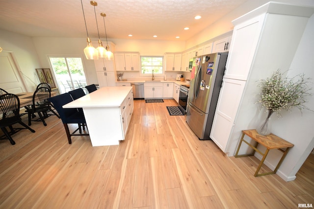 kitchen featuring hanging light fixtures, appliances with stainless steel finishes, sink, white cabinetry, and a center island