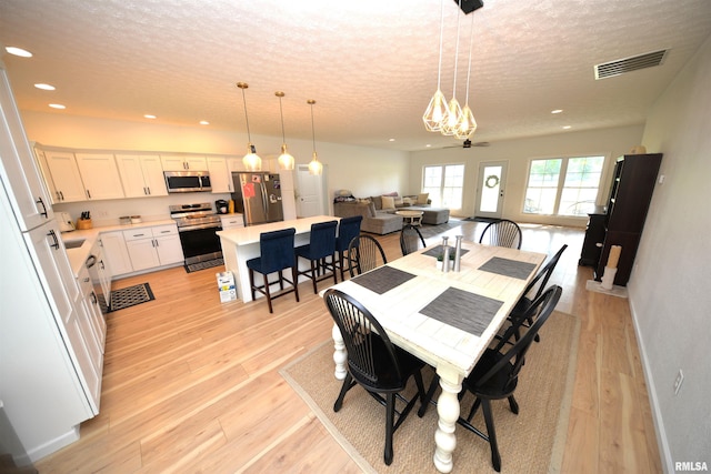 dining room featuring ceiling fan, a textured ceiling, and light wood-type flooring