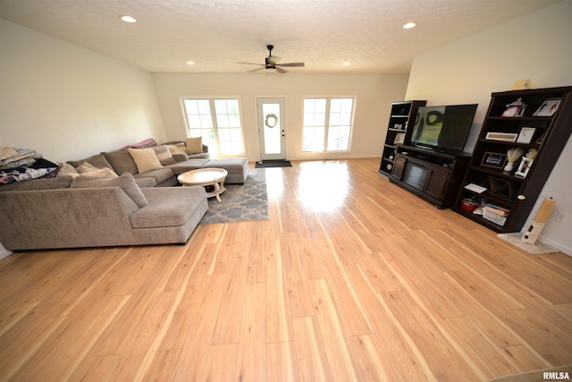 living room featuring a textured ceiling, light hardwood / wood-style flooring, and ceiling fan