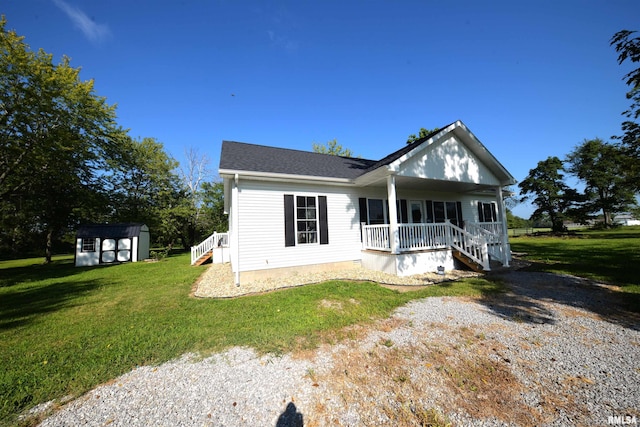 view of front of property featuring covered porch, a front yard, and a storage shed