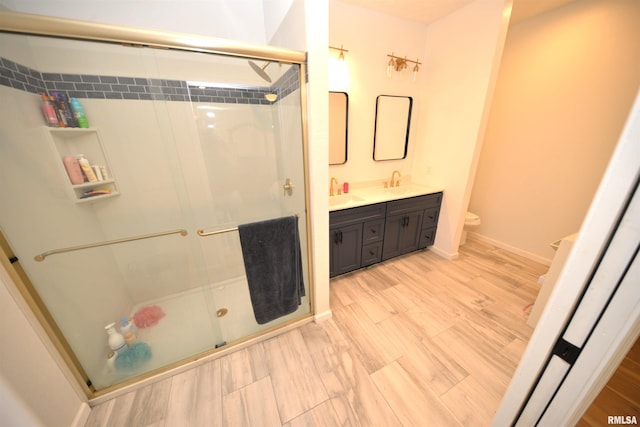 bathroom with wood-type flooring, an enclosed shower, vanity, and toilet