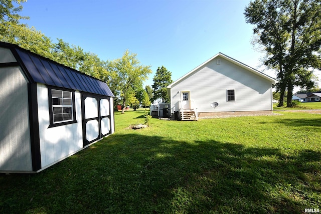 view of yard with central air condition unit and an outbuilding