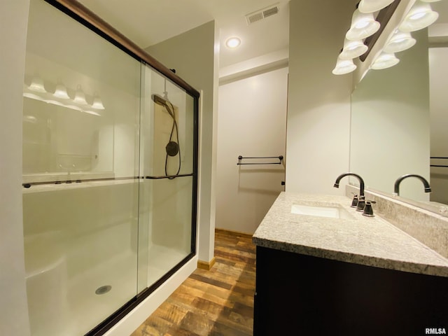 bathroom featuring wood-type flooring, a shower with shower door, and vanity