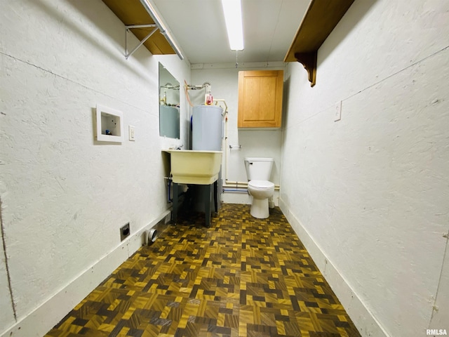 laundry room featuring gas water heater, washer hookup, and dark parquet flooring