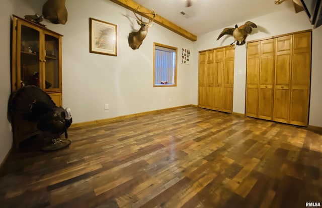 unfurnished bedroom featuring two closets, dark hardwood / wood-style flooring, and lofted ceiling with beams