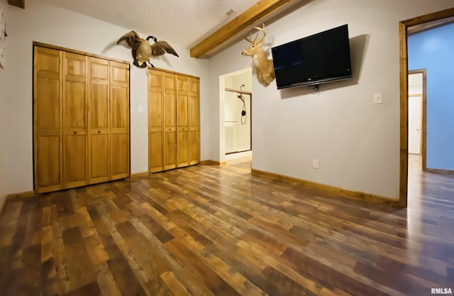 unfurnished bedroom with multiple closets, vaulted ceiling with beams, and dark hardwood / wood-style flooring