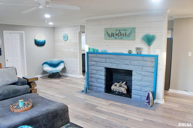 living room featuring hardwood / wood-style flooring, ceiling fan, ornamental molding, and a fireplace