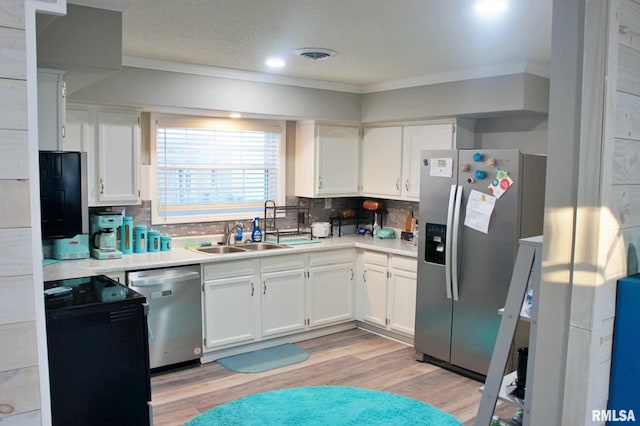 kitchen with light hardwood / wood-style floors, white cabinetry, decorative backsplash, sink, and stainless steel appliances