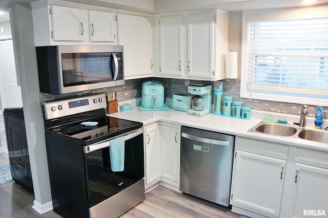 kitchen with white cabinets, stainless steel appliances, decorative backsplash, and sink