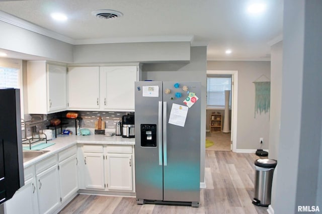 kitchen featuring stainless steel refrigerator with ice dispenser, white cabinetry, light wood-type flooring, and tasteful backsplash