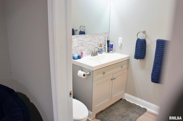 bathroom featuring backsplash, toilet, and vanity