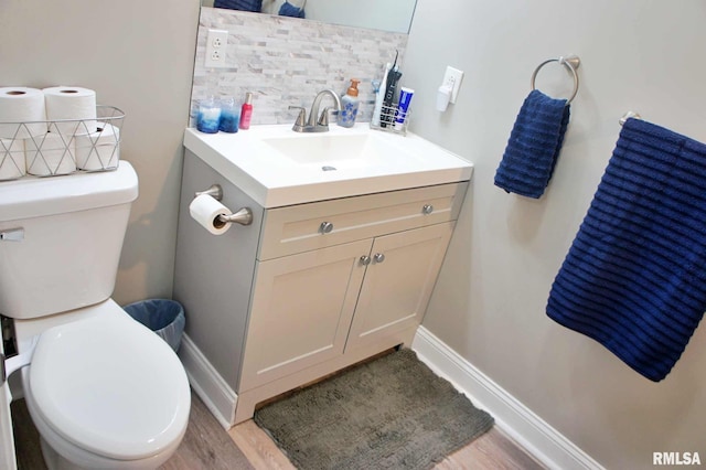 bathroom with toilet, hardwood / wood-style floors, tasteful backsplash, and vanity