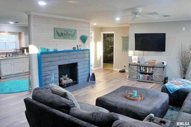 living room featuring sink, a brick fireplace, ornamental molding, and light hardwood / wood-style floors