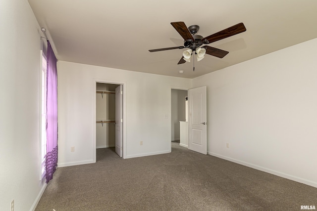 unfurnished bedroom featuring ceiling fan, a closet, a walk in closet, and dark colored carpet