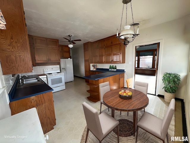 kitchen with sink, white appliances, backsplash, hanging light fixtures, and ceiling fan with notable chandelier