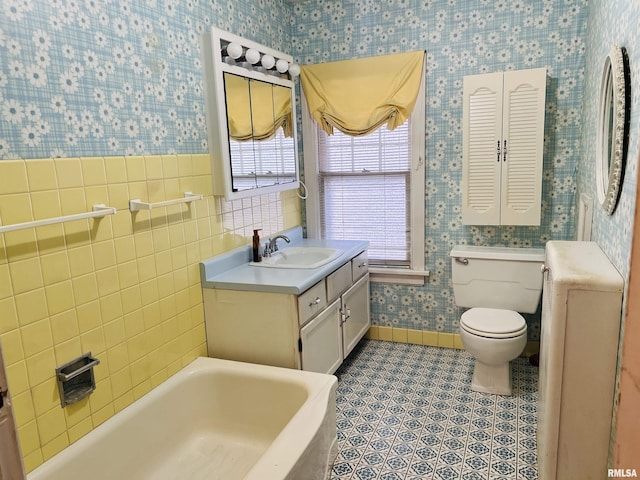 bathroom featuring tile patterned floors, toilet, tile walls, vanity, and a tub