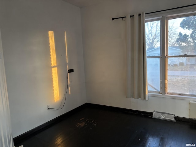 empty room with plenty of natural light and dark hardwood / wood-style flooring